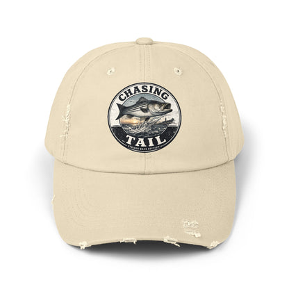 A beige distressed baseball cap featuring a circular embroidered patch on the front with a fish and the text 'CHASING TAIL'.